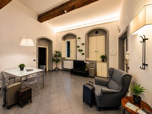 A spacious living area with a dining table, chairs, a sofa, and a TV. There are potted plants and a lamp. - Red Door Dream Apartment 3 (Firenze)