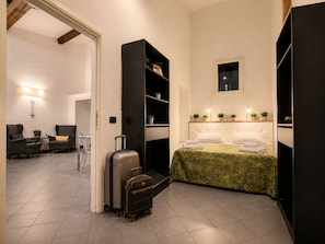 A hotel room with a bed, a seating area with chairs, a large wardrobe, and a suitcase. - Red Door Dream Apartment 3 (Firenze)