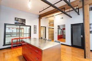 A modern office space with a large central table, red cabinets, and a glass display case. - Top-Floor Suite in Exchange District | 2 Bed | 2 Bath | (Winnipeg)