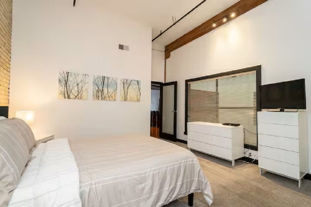 A bedroom with a bed, a dresser, a television, and wall art.