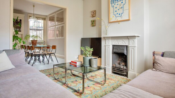 A living room with a fireplace, a dining area with chairs and a table, and a sofa. - Spacious 4-Bedroom Victorian Townhouse | Sleeps 8 | Central London (E1) (London)