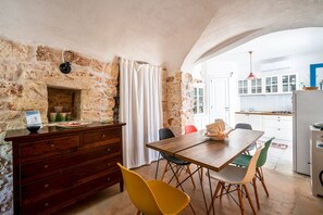 A dining area with a stone wall, wooden table, and chairs. - Torrette di Ostuni · Trullo with private pool in olive grove, dogs welcome (Ostuni)
