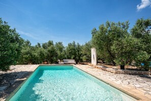 A rectangular swimming pool with clear water, surrounded by stone walls and trees. - Torrette di Ostuni · Trullo with private pool in olive grove, dogs welcome (Ostuni)