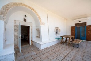A room with a stone archway, a wooden table, and a blue door. - Torrette di Ostuni · Trullo with private pool in olive grove, dogs welcome (Ostuni)
