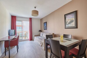 Une pièce comprenant une table à manger, des chaises, un canapé, un téléviseur et un balcon avec vue.