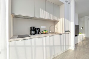 A modern kitchen with a built-in sink, a coffee maker, and a bowl of fruit. - Breeze & Pine - Wave Resort & Spa (Międzyzdroje)