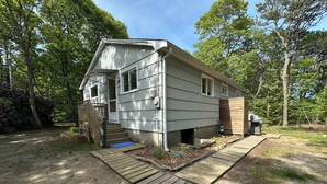 A single-story mobile home with a front porch, a small deck, and a wooden fence.
