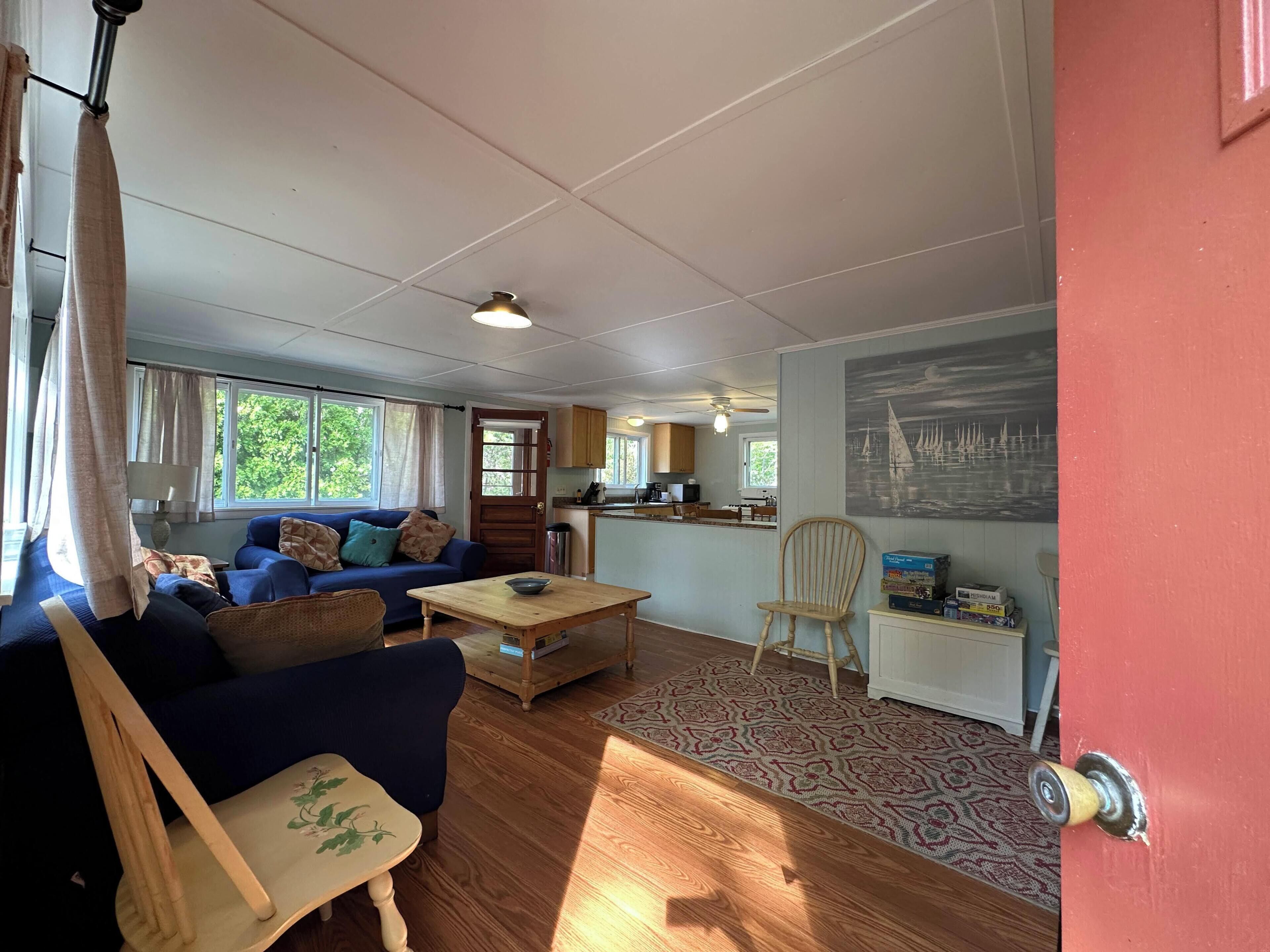 Et værelse med sofa, spisebord, stol, tekøkken og en dør med et billede.