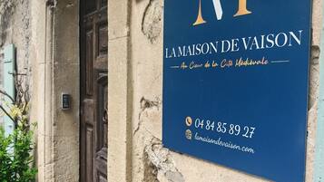 A sign for 'La Maison de Vaison' with a medieval theme, including a phone number and website.