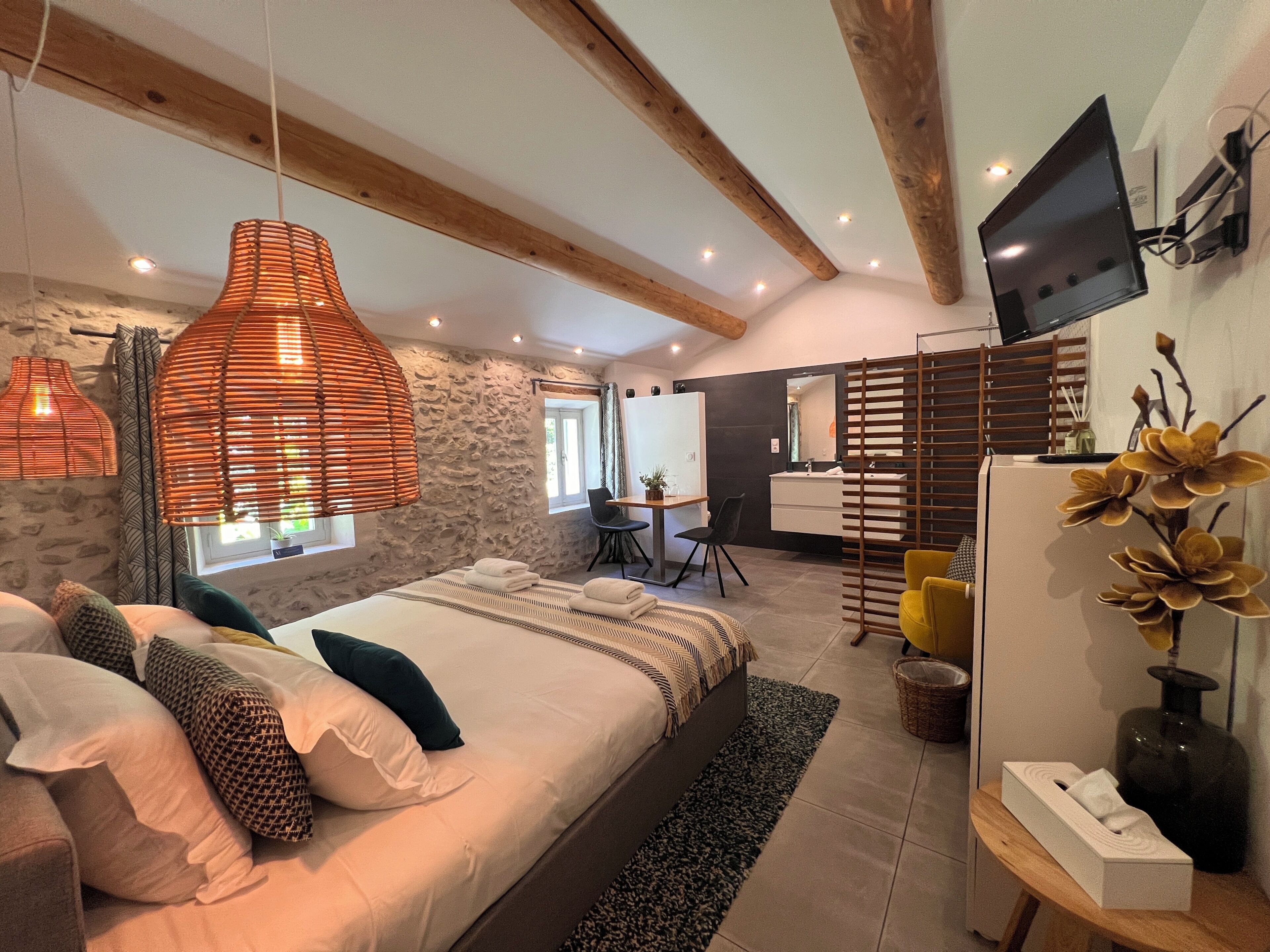 A modern bedroom with a large bed, a desk, and a television.