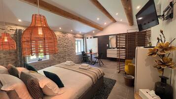 A modern bedroom with a large bed, a desk, and a television.