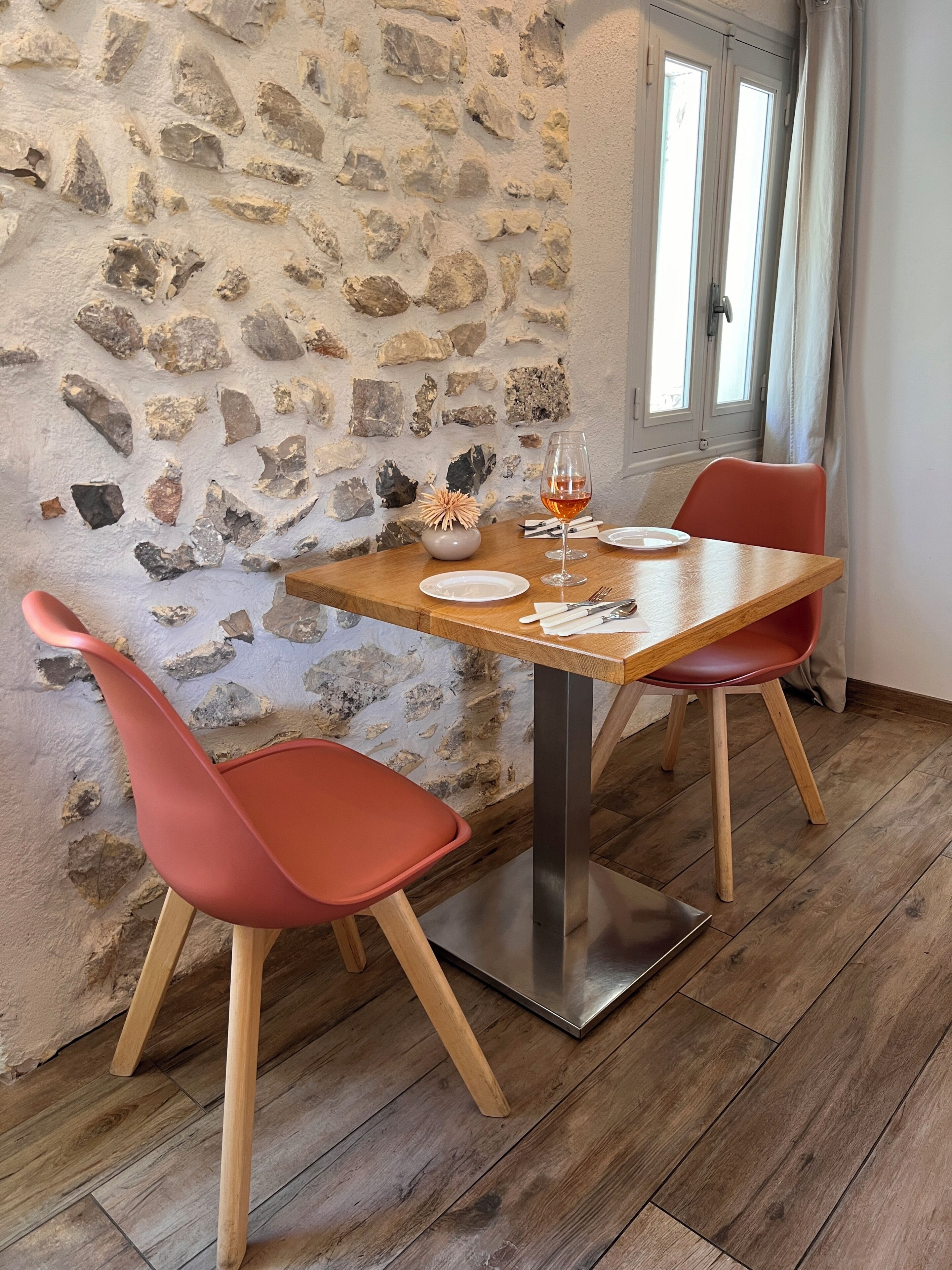 Un coin repas avec un mur en pierre, une table en bois et des chaises rouges.