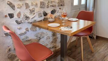 Un coin repas avec un mur en pierre, une table en bois et des chaises rouges.