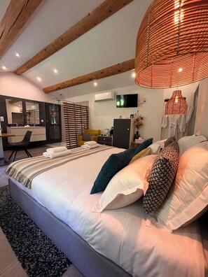 Ein modernes Schlafzimmer mit einem großen Bett, einer Sitzecke und einem Fernseher.