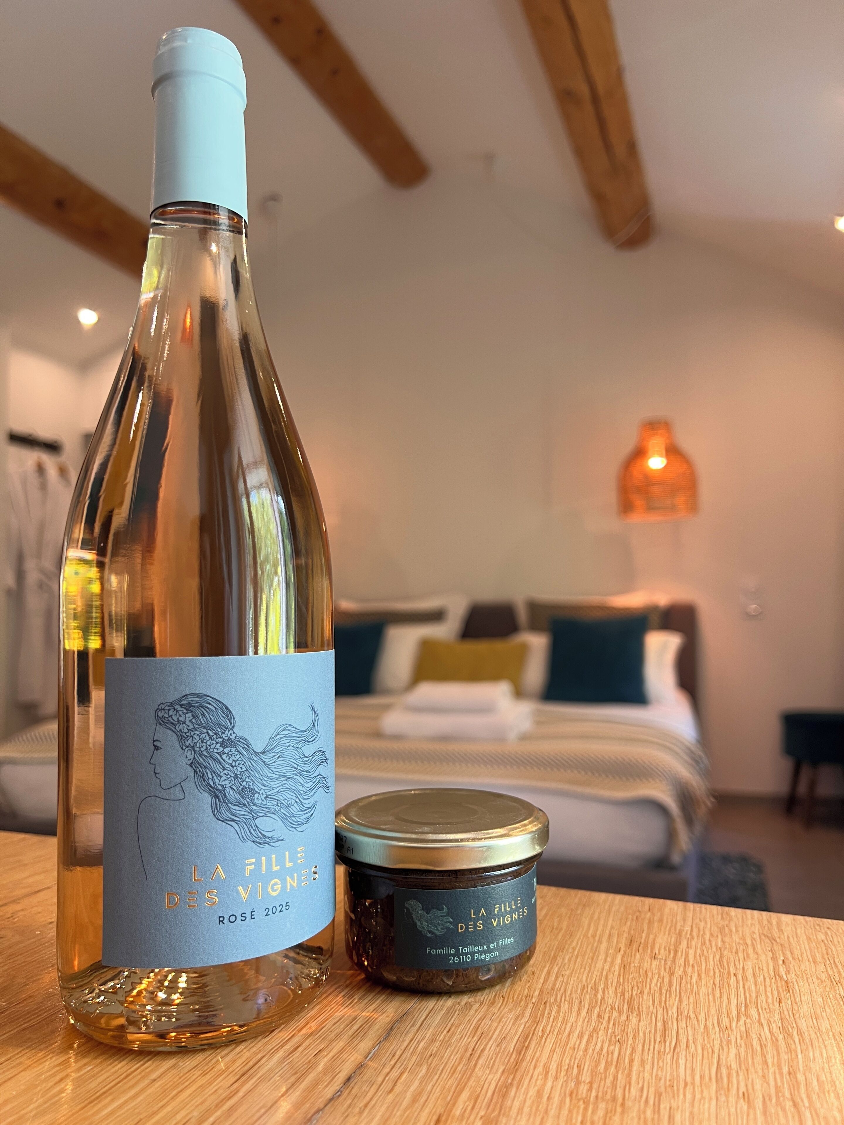 Una botella de vino y un tarro de mermelada sobre una mesa de madera en una habitación de hotel.