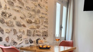Ein Essbereich mit einer Steinsäule, einem Holztisch, zwei roten Stühlen und einem Weinglas.