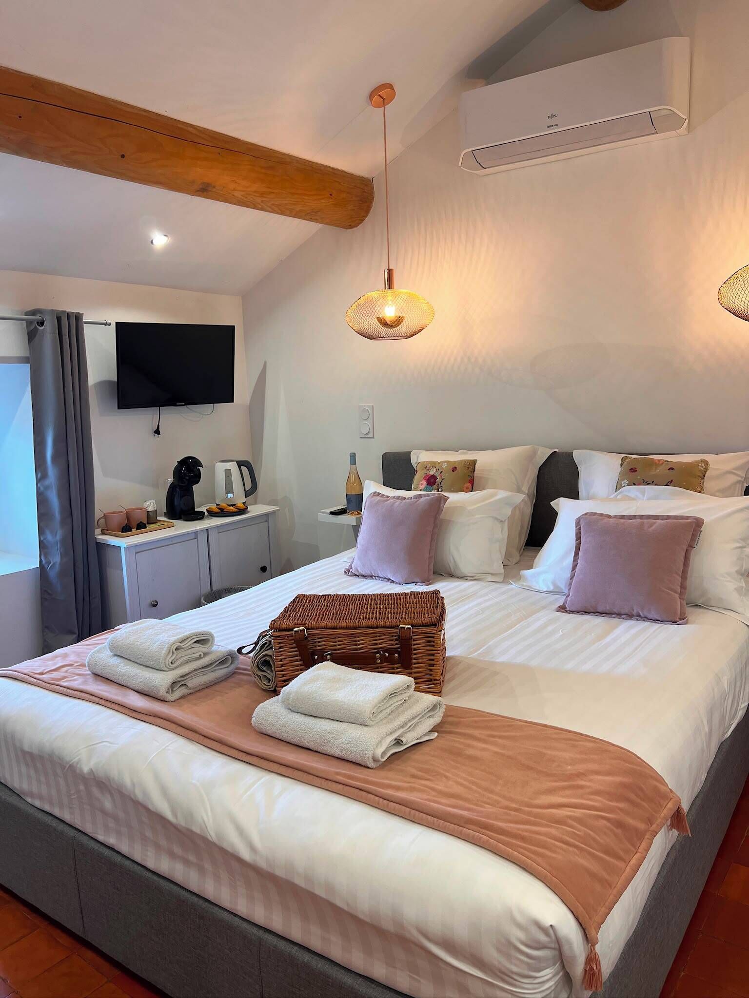 A hotel room with a bed, bedside table, TV, and a large window.