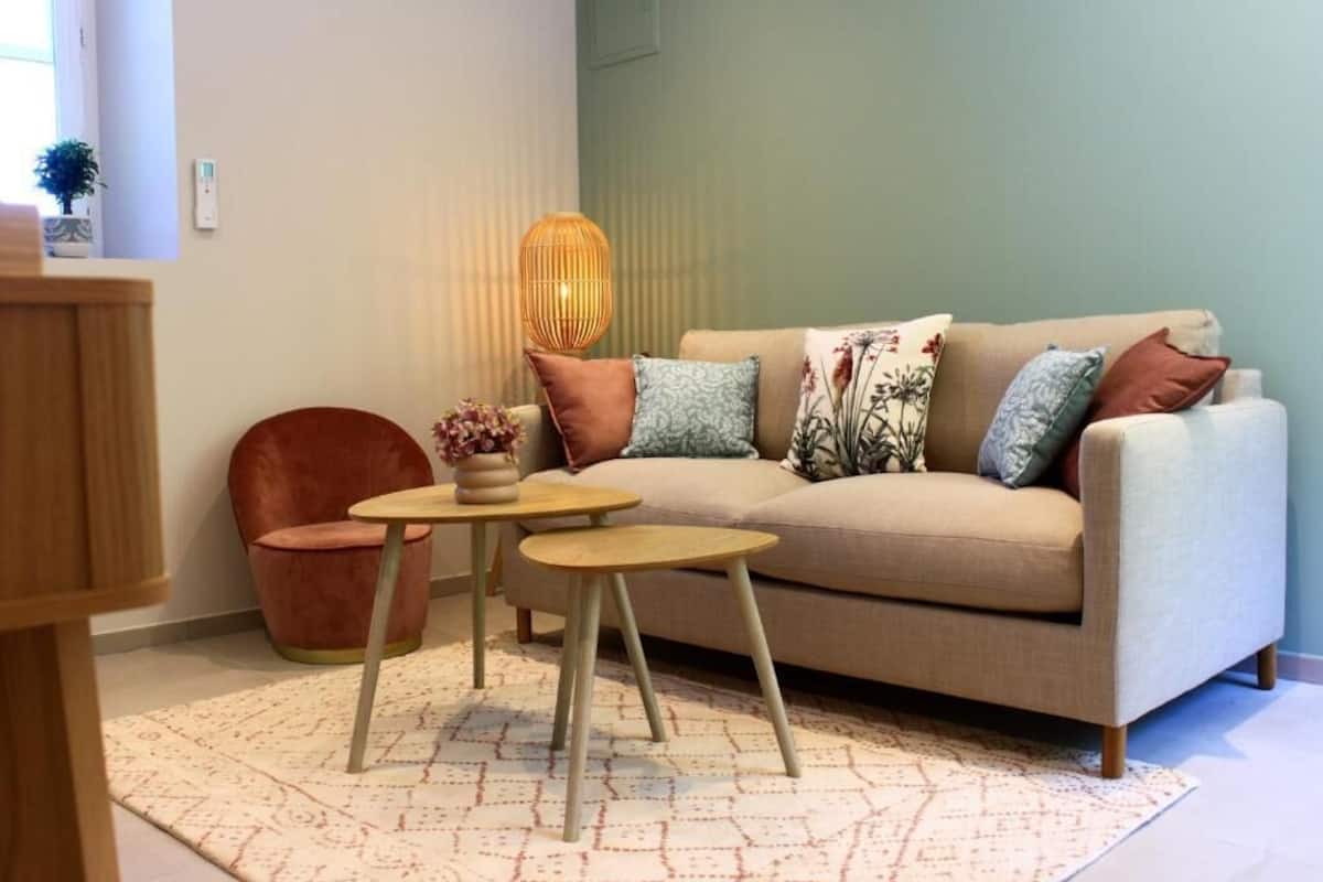 Ein Wohnzimmer mit einer Couch, zwei kleinen Tischen, einem Sessel und einer Stehlampe.