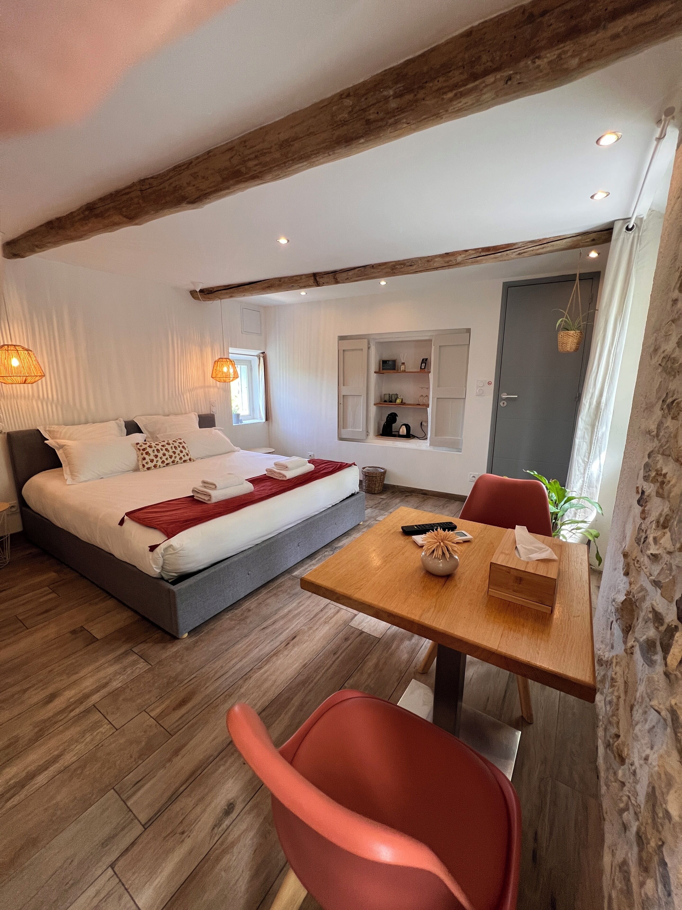 A modern bedroom with a bed, bedside table, and a small seating area with a table and chair.