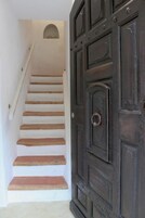 A staircase leading to a dark wooden door with a circular handle.