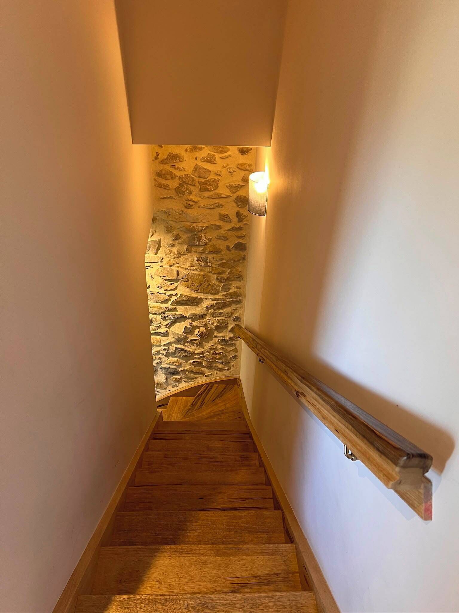 A wooden staircase with a stone wall at the top.