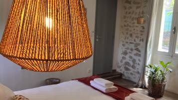 A bedroom with a large bed, a hanging lamp, and a potted plant.