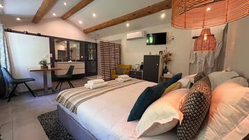 A modern bedroom with a large bed, bedside tables, a desk, and a television.