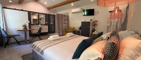 A modern bedroom with a large bed, bedside tables, a desk, and a television.