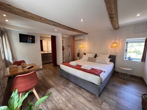 Ein Schlafzimmer mit Bett, Nachttisch, Stuhl und Fernseher an der Wand.