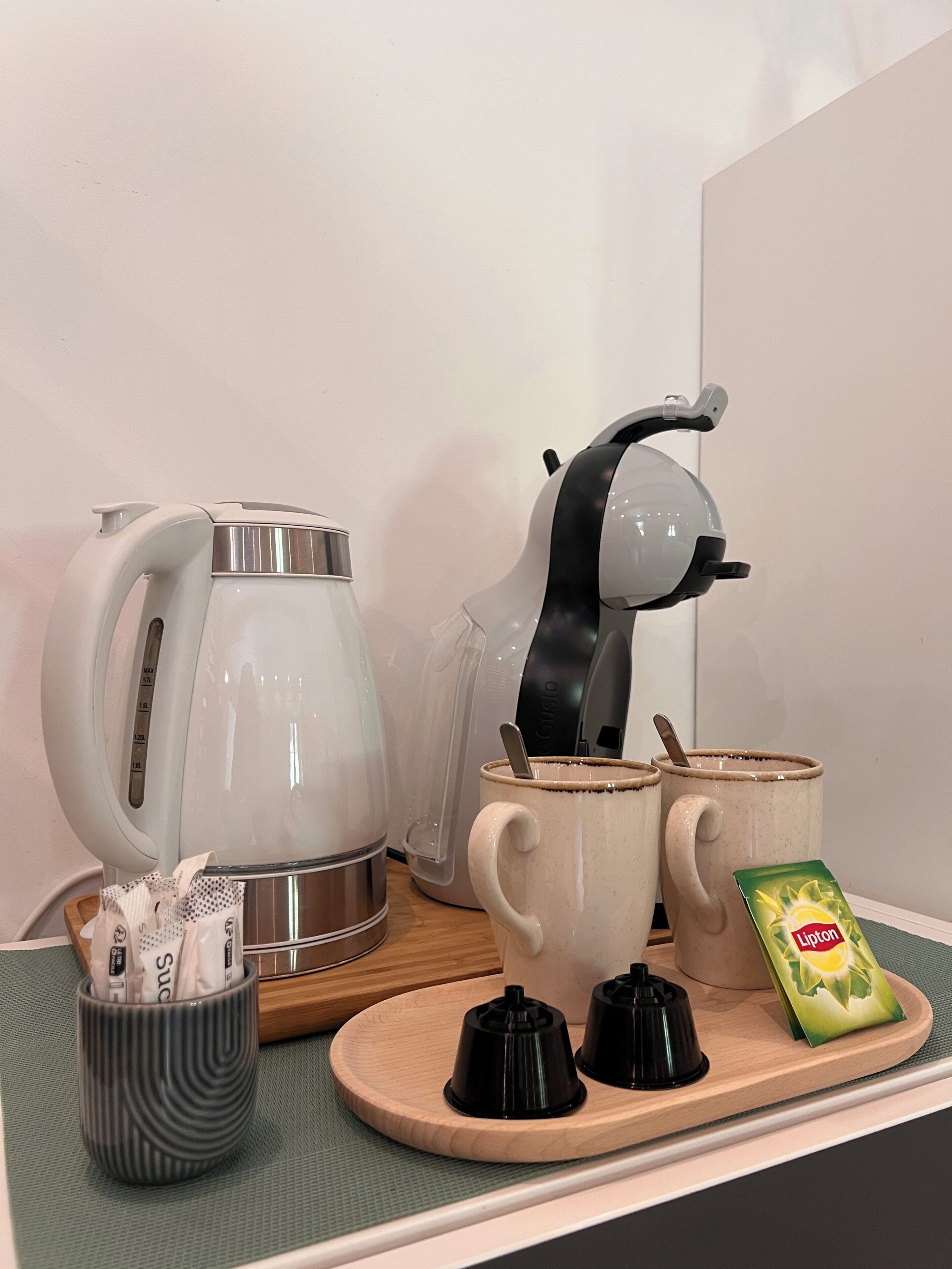 Een keukentrap met een waterkoker, een koffiezetapparaat, twee mokken, een theezakje en een pakje Lipton thee.