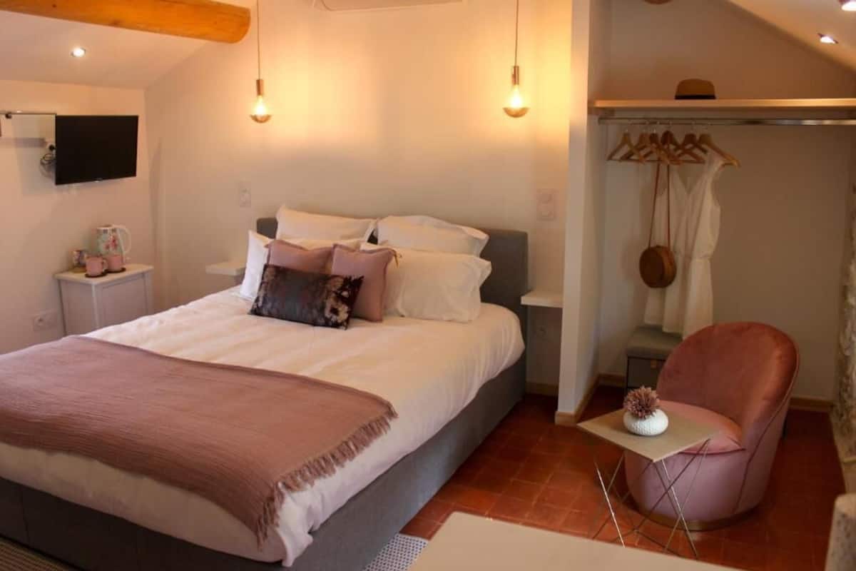 Ein Schlafzimmer mit Bett, Nachttischen, einem Sessel, einem Fernseher und einem Kleiderschrank.