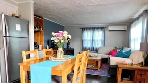 A living room with a dining area, a sofa, a TV, and an air conditioning unit.