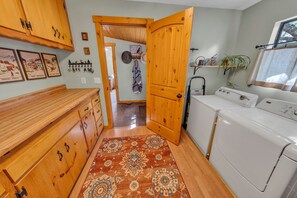 A laundry area with wooden cabinets, a washing machine, and a patterned rug. - Rustic Retreat w/ Deck! Dog Friendly| 2BR+Office (Prescott)
