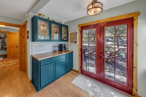 A kitchen with teal cabinets, a wooden countertop, a red door with glass panels, and a visible outdoor area with furniture. - Rustic Retreat w/ Deck! Dog Friendly| 2BR+Office (Prescott)