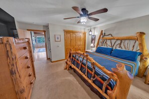 A bedroom with a wooden headboard, a ceiling fan, a bed with blue bedding, and a wooden dresser. - Rustic Retreat w/ Deck! Dog Friendly| 2BR+Office (Prescott)