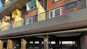 Ein mehrstöckiges Gebäude mit Balkonen, einem überdachten Parkbereich und einer Ziegel-Fassade.