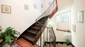 Eine Treppe mit Holzbalkon und schwarzen Pfosten, die zu einer oberen Etage führt.
