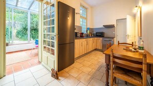 Eine Küche mit Kühlschrank, Mikrowelle und Herd. Ein Esstisch mit Stühlen steht bereit.