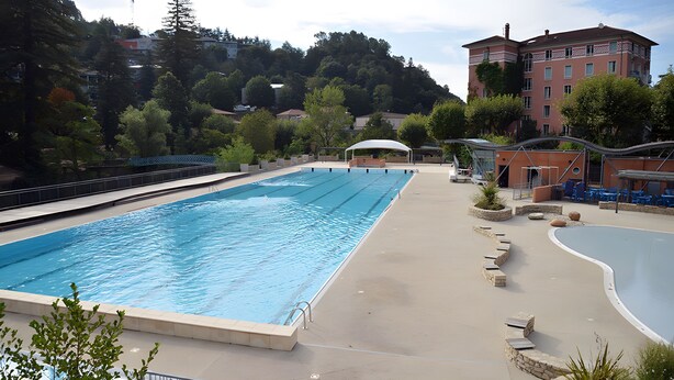A swimming pool with a surrounding deck, a covered seating area, and a building in the background. - Studio "Papillon" with Mountain View, Wi-Fi, and Air Conditioning (Vals-les-Bains)