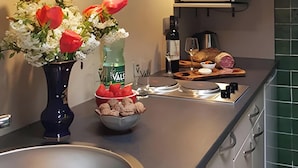 A kitchen with a sink, a vase with flowers, a microwave, and a countertop with food items. - Studio "Papillon" with Mountain View, Wi-Fi, and Air Conditioning (Vals-les-Bains)