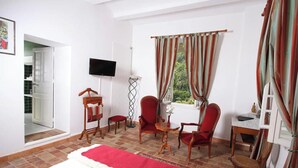 A hotel room with a bed, a TV, a desk, two chairs, a small table, and a window with curtains. - Studio "Papillon" with Mountain View, Wi-Fi, and Air Conditioning (Vals-les-Bains)
