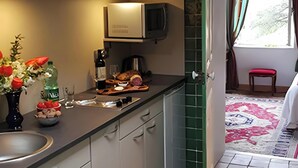 A kitchen with a built-in microwave, a sink, and a dining area with a chair. - Studio "Papillon" with Mountain View, Wi-Fi, and Air Conditioning (Vals-les-Bains)