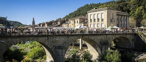 A stone bridge with arches over a river, surrounded by greenery and buildings.