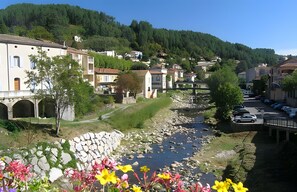 A riverside town with stone walls, a bridge, and parked cars. - Studio “Mediterranean” with Mountain View, Shared Pool, and Wi-Fi (Vals-les-Bains)