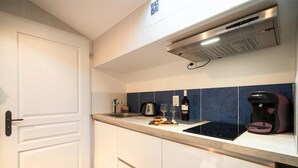 Una cocina con una puerta blanca, una cafetera, un tostador y una botella de vino sobre la encimera.