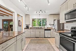 Eine moderne Küche mit Granit Arbeitsplatten, Edelstahlgeräten und einem großen Fenster.