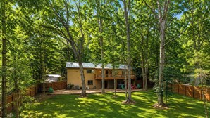 Une maison à deux étages avec un patio couvert et une cour arrière clôturée.