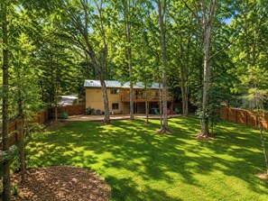 Ein zweistöckiges Haus mit einer überdachten Terrasse und einem eingezäunten Garten.