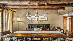 A rustic dining room with a wooden table, chairs, and hanging crystal chandeliers. - Historic Adobe, Kiva Fireplace, Walk to Canyon Rd (Santa Fe)