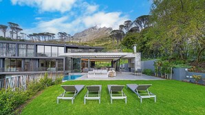 A modern house with a pool, outdoor seating, and a view of the mountains. - Tarentaal Kloof Villa in Higgovale. (Cape Town)